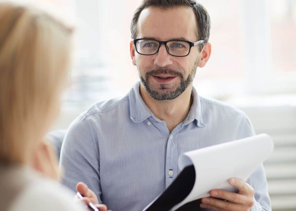 Confident counselor with document giving advice to his patient while discussing ways of solving her problem