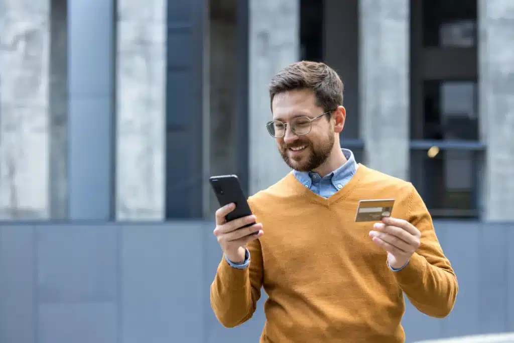 Person holding an insurance card while using a laptop