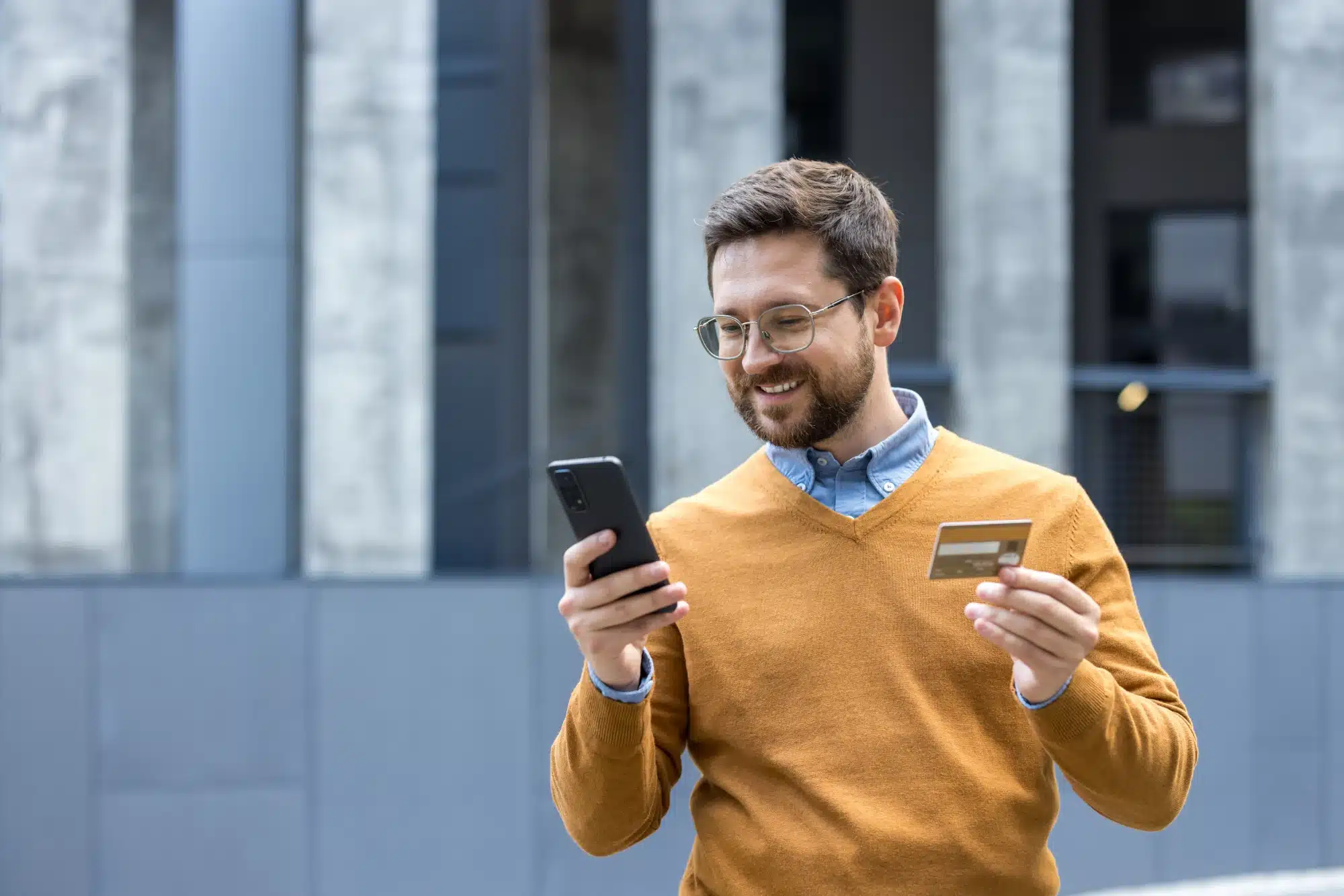 Person holding an insurance card while using a laptop